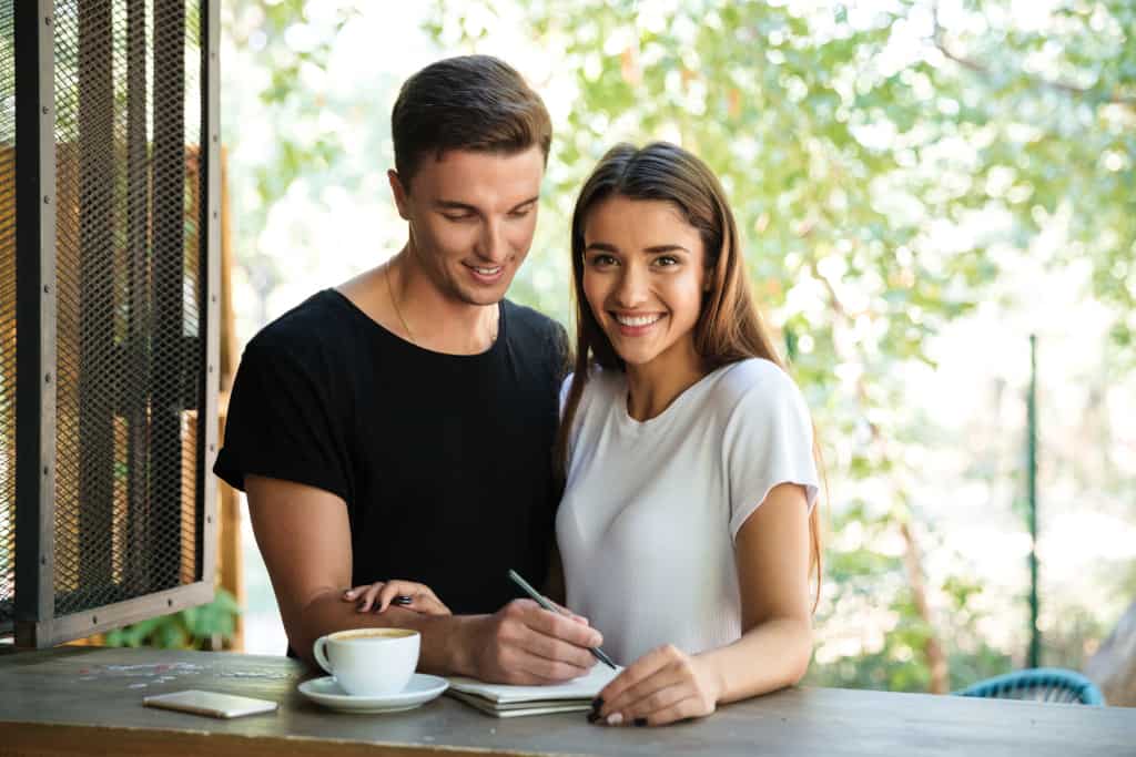 Smiling young couple making guest list together