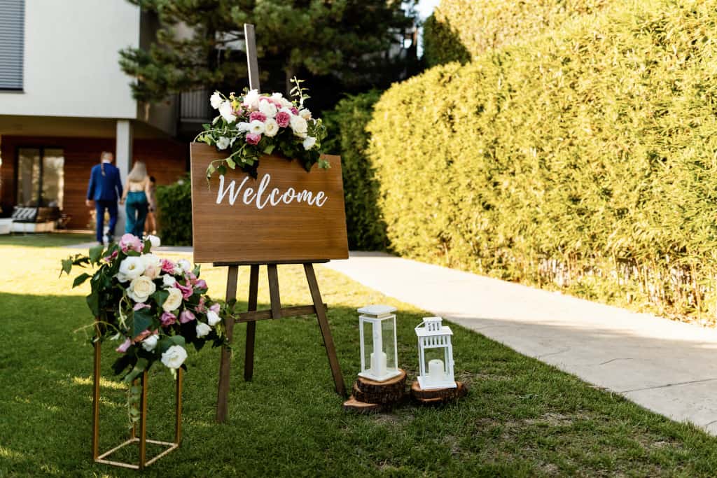 Welcome board at wedding reception in a garden.