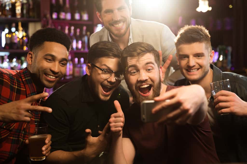 Happy male friends taking selfie and drinking beer at bachelor party